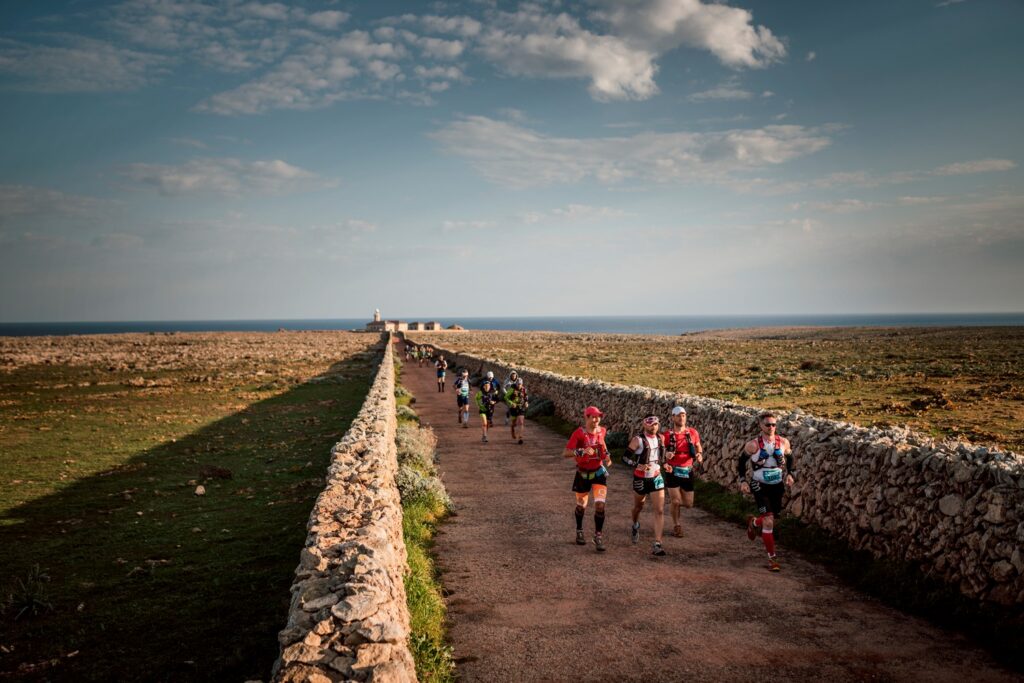 Corredors entre parets de pedra seca, amb el far de Punta Nati al fons (Foto: The Adventure Bakery).